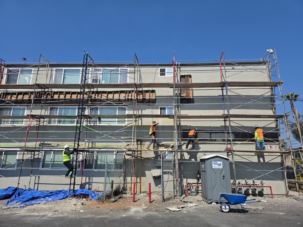 Junk Tigers crew on scaffolding for balcony demolition at a three-story apartment building
