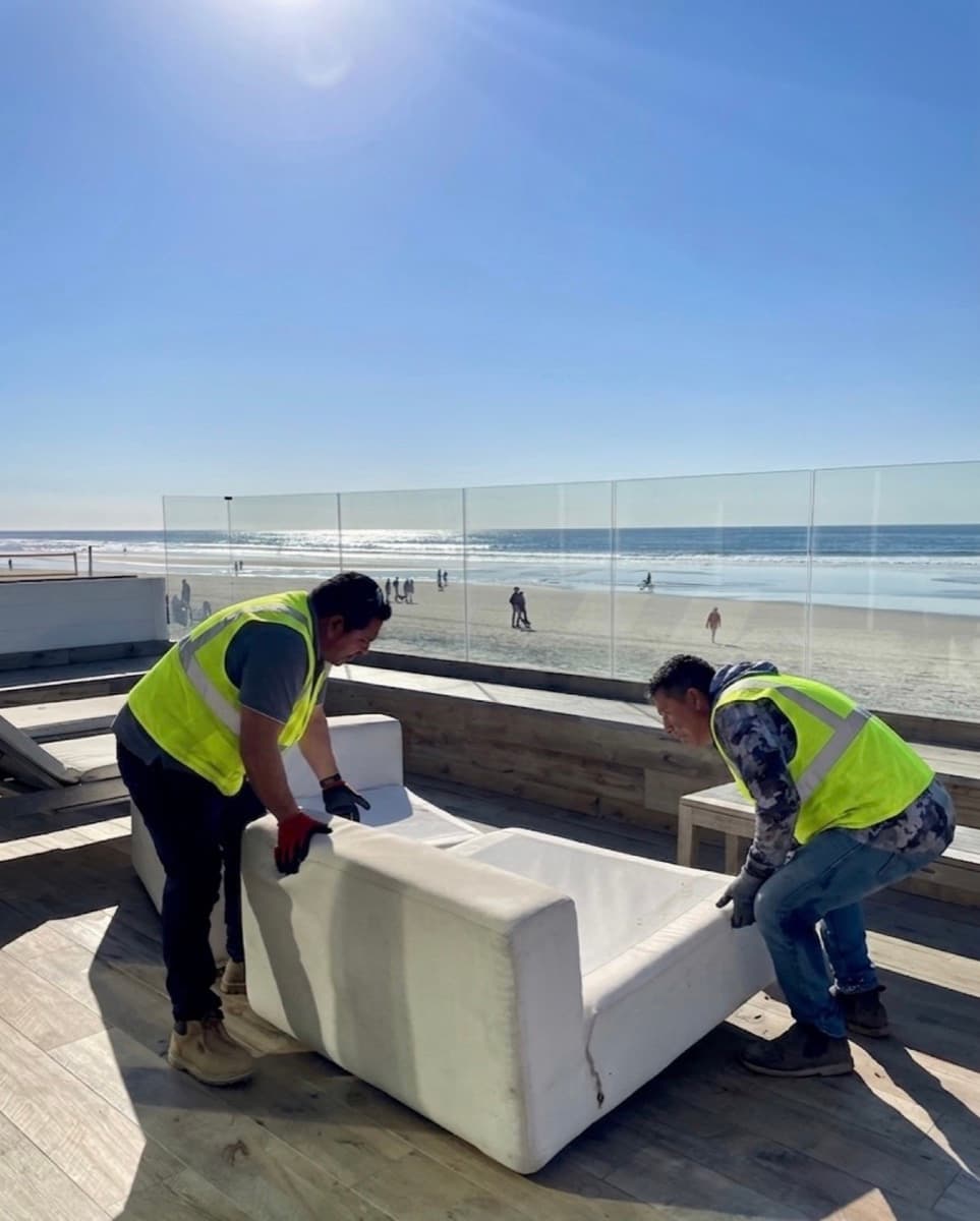 Junk Tigers crew removing a couch from an oceanfront deck