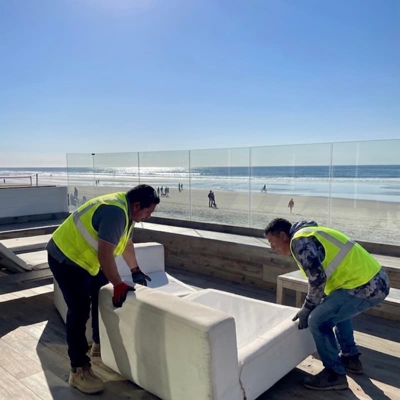 Junk Tigers crew removing a couch from an oceanfront deck